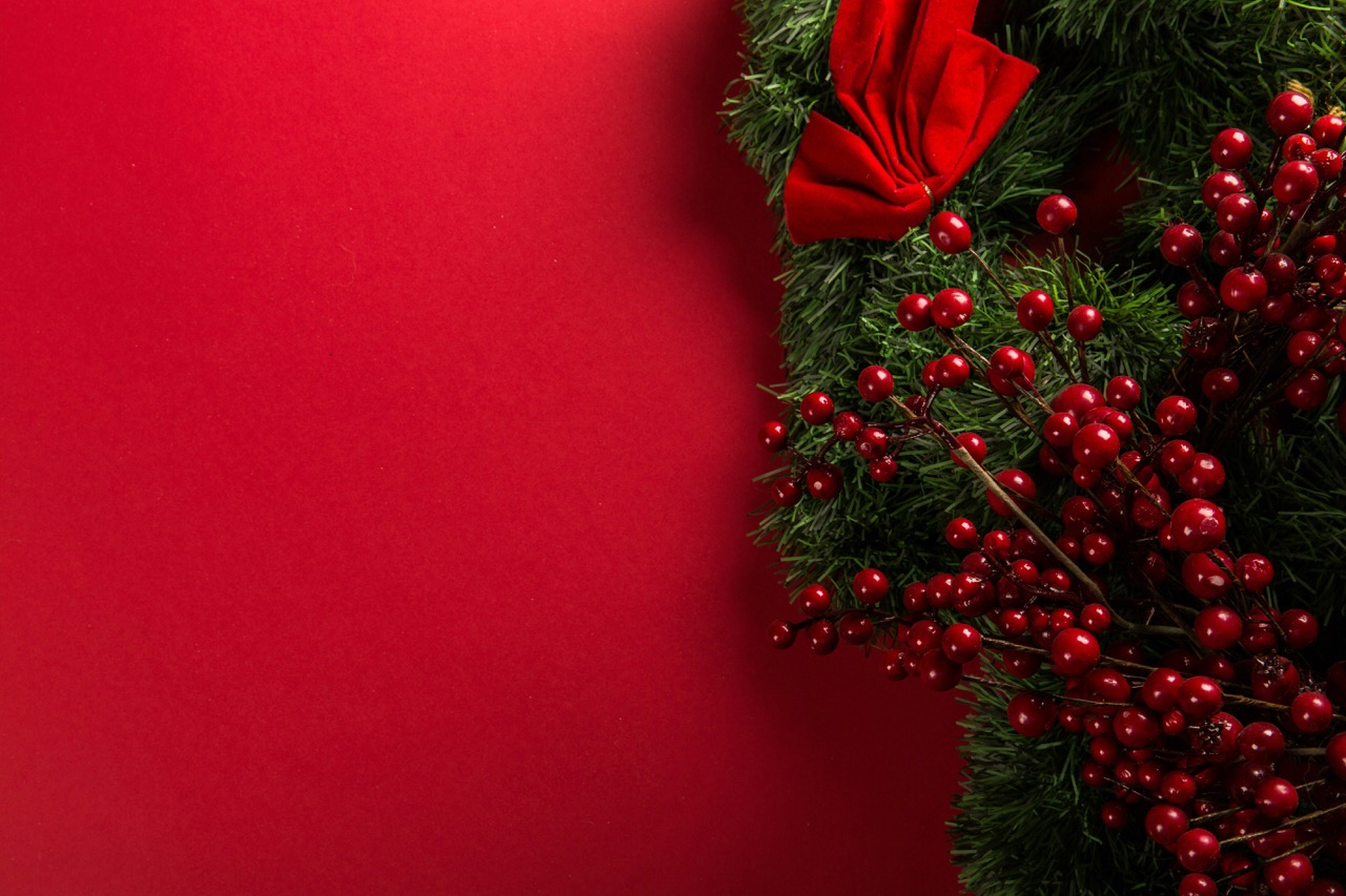 A Christmas wreath with red berries and a velvet bow